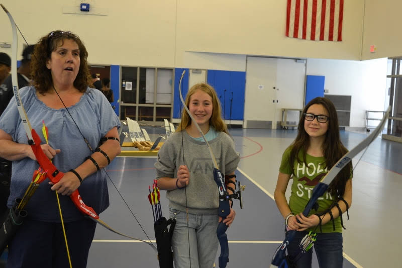 A parent and two kids smiling with their bows